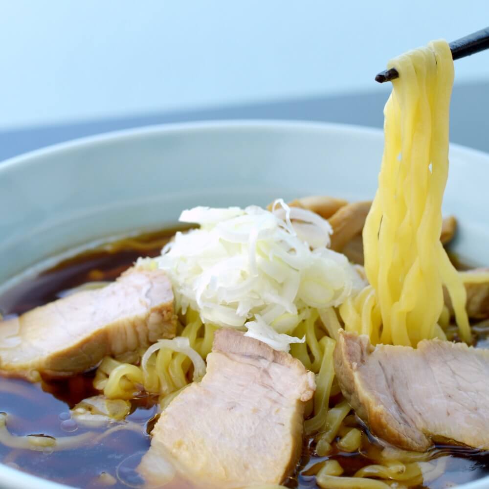 商品名:喜多方、多加水 熟成の平打ち太麺・ちぢれ麺のあっさり醤油ラーメンの麺持ち上げ